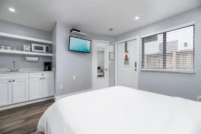 a white bedroom with a large bed and a tv at Shell on the Beach 103 - RENOVATED in Hollywood