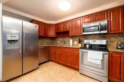 a kitchen with wooden cabinets and stainless steel appliances at Shell on the Beach 101 in Hollywood