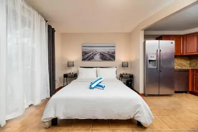 a bedroom with a large bed and a refrigerator at Shell on the Beach 101 in Hollywood