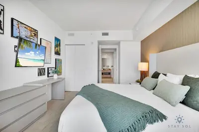 a white bedroom with a large bed and a desk at Ocean View Balcony, Beachfront Resort, Amazing Pool in Hollywood