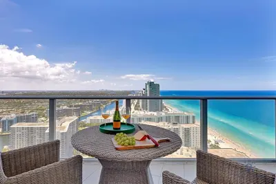 a table with a plate of food and a bottle of wine on a balcony at Ocean View Balcony, Beachfront Resort, Amazing Pool in Hollywood