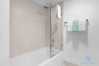 a white bathroom with a shower with a glass door at Infinite View, Balcony, Gym, Amazing Pool in Hallandale Beach