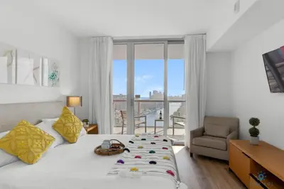 a bedroom with a bed and a chair and a window at Infinite View with Balcony,Pool plus Near Beach in Hallandale Beach