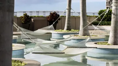 a group of hammocks in a pool with palm trees at Four Seasons Studio - Privately Owned Unit in Miami