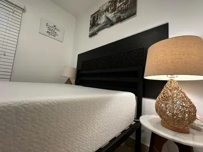a bedroom with a bed and a lamp on a table at Private Rooms in Miami