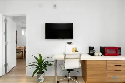 a room with a desk and a tv on a wall at Infinite View and Balcony with Pool, Near Beach in Hallandale Beach