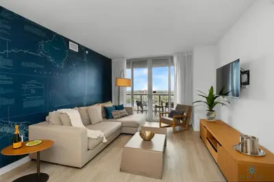 a living room with a white couch and a blue wall at Infinite View and Balcony with Pool, Near Beach in Hallandale Beach