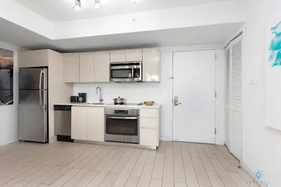 a kitchen with white cabinets and a stainless steel refrigerator at Infinite View with Balcony, Gym, Pool in Hallandale Beach