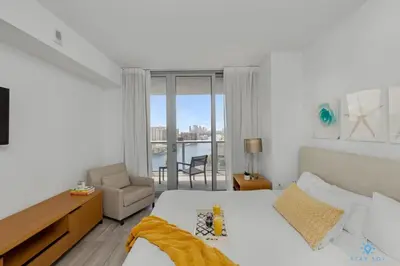 a bedroom with a bed and a chair and a window at Infinite View with Balcony, Gym, Pool in Hallandale Beach