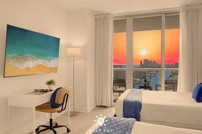a hotel room with a bed and a desk and a window at Infinite View - Balcony - Pool - Gym - Near Beach in Hallandale Beach
