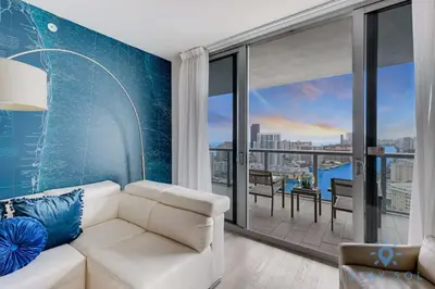 a living room with a white couch and a balcony at Infinite View - Balcony - Pool - Gym - Near Beach in Hallandale Beach
