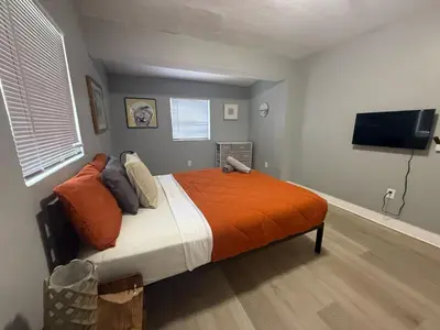 a bedroom with a bed with an orange blanket and a flat screen tv at Modern cozy home with private patio - Sleeps 6 in Miami