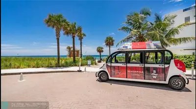 a small car parked next to a beach with palm trees at Stylish Miami Beach Getaway, Ocean Views & Gourmet Kitchen -12A in Hallandale Beach