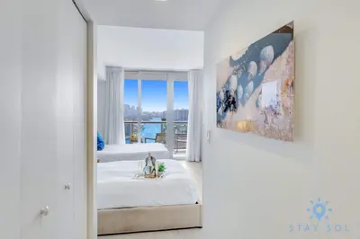 a white room with two beds and a mirror at Spacious 2BR Condo, Sleeps 6, Beachwalk Resort in Hallandale Beach
