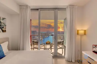 a bedroom with a bed and a balcony with a view at BeachWalk Resort, Views, Balcony, Studio in Hallandale Beach