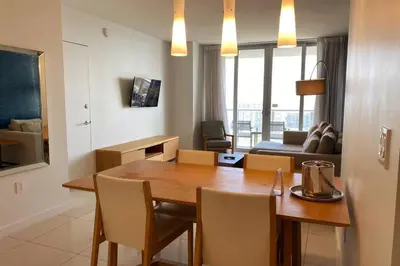 a kitchen and living room with a table and chairs at Upscale Beach Apartment, Style, Views & Complete Kitchen -28A in Hallandale Beach