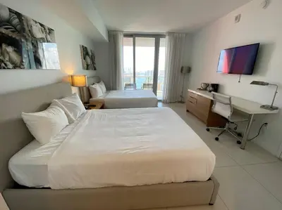 a bedroom with two beds and a desk with a computer at Miami Beach Glam, Ocean Views & Elegance -28B in Hallandale Beach