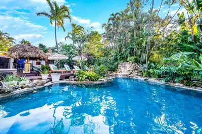a swimming pool in the middle of a tropical yard with palm trees at Tropical Jungle Pool Oasis in Fort Lauderdale