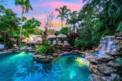 a waterfall in the middle of a pool in a backyard at Tropical Jungle Pool Oasis in Fort Lauderdale