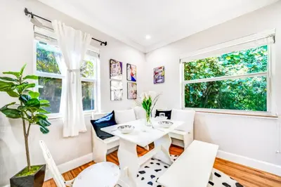 a dining room with white furniture and windows at Tropical Jungle Pool Oasis in Fort Lauderdale