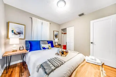 a bedroom with a large white bed with blue pillows at Tropical Jungle Pool Oasis in Fort Lauderdale