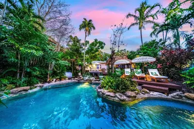 a pool in a backyard with chairs and trees at Tropical Jungle Pool Oasis in Fort Lauderdale