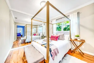 a bedroom with a canopy bed and a living room at Tropical Jungle Pool Oasis in Fort Lauderdale