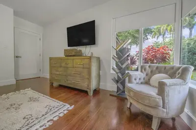 a living room with a chair and a tv and a dresser at Boho House - Stylist Home with Parking and large Yard in Miami
