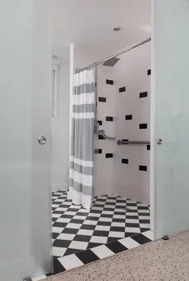 a bathroom with a shower with a black and white checkered floor at The Vagabond Hotel Miami in Miami