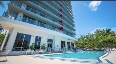 a building with a swimming pool in front of a building at Stunning Penthouse Suite Waterfront 2BD 2BA in Hallandale Beach