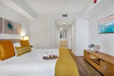 a white bedroom with a large bed and a table at Apartment with Balcony, Gym & Near Beach in Hallandale Beach