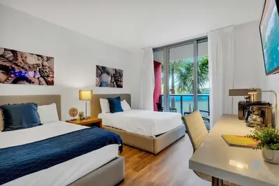 a hotel room with two beds and a desk and a window at Modern Resort - Apartment with Balcony, Pool and Gym in Hallandale Beach
