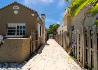 a fence next to a house and a sidewalk at Bike to Beach-Spacious With Patio BBQ & Game Room (Pet-Friendly) in Hallandale Beach