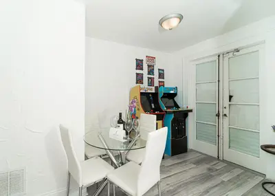 a dining room with a glass table and white chairs at Bike to Beach-Spacious With Patio BBQ & Game Room (Pet-Friendly) in Hallandale Beach