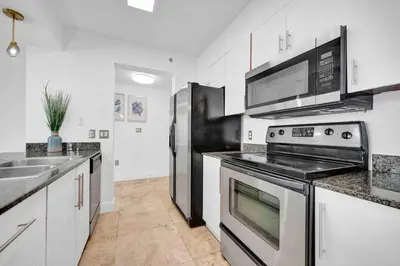 a kitchen with stainless steel appliances and white cabinets at 40th Floor Priceless Unit Central Location in Miami