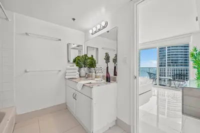 a white bathroom with a sink and a tub and a window at High Floor Ocean view Unit In Brickell in Miami