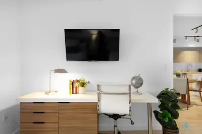a desk with a chair and a television on a wall at Infinite View - Balcony- Amazing Pool- Near Beach in Hallandale Beach
