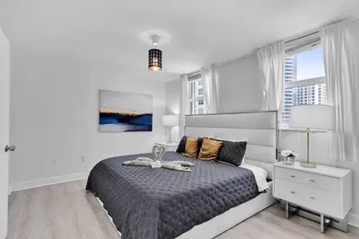 a bedroom with a bed with a gray bedspread and a lamp at Modern 2/2 with Beautiful Ocean and Brickell Views in Miami