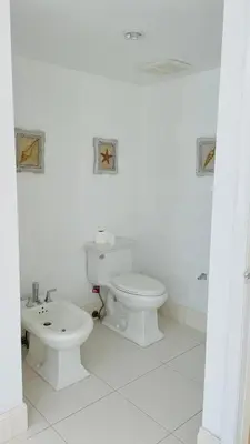 a white bathroom with a toilet and a sink at Beachfront Apt in Carlyle Hotel on Ocean Drive in Miami Beach