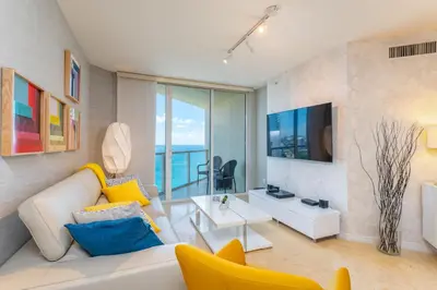 a living room with a white couch and a tv at 16699 Collins Ave Unit 2906 in La Perla in Miami Beach