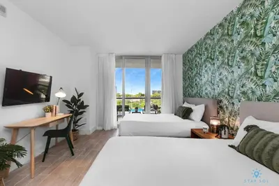 a hotel room with two beds and a desk and a window at Tropical Apartment - Balcony - Resort with Pool and Gym in Hallandale Beach