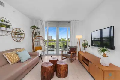 a living room with a couch and two wooden stools at Tropical Apartment - Balcony - Resort with Pool and Gym in Hallandale Beach