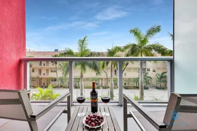 a table with two glasses of wine on a balcony at MODERN Resort Modern apartment 2 BR 2 BR POOL in Hallandale Beach
