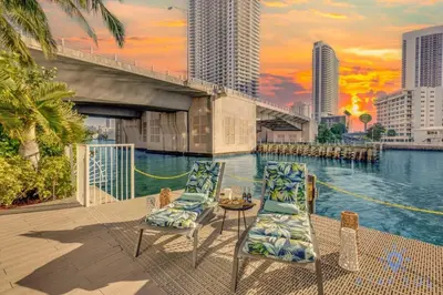 a couple of chairs and a table next to the water at MODERN Resort Modern apartment 2 BR 2 BR POOL in Hallandale Beach