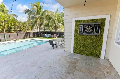 a backyard with a pool and a dartboard on a wall at UPSCALE MANSION IN THE HEART OF MIAMI WITH POOL in Miami
