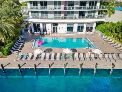 an aerial view of a pool with chairs and a building at Tropical Apartment - Balcony - Resort, Pool - Gym in Hallandale Beach