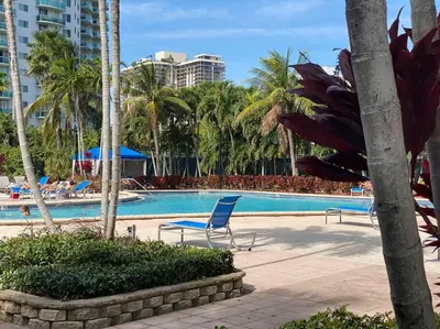 a swimming pool with two chairs and palm trees at Breathtaking ocean view! 15th floor in Miami Beach