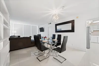 a dining room with a glass table and black chairs at Oceanfront Luxury Condo - Private Beach Access, Pool & Game Room in Hollywood