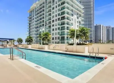 a swimming pool in front of a tall building at Modern Vacation Apartment in Miami in Miami