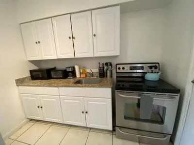 a kitchen with white cabinets and a stove at Small House Near Airport Beach - Wynwood in Miami